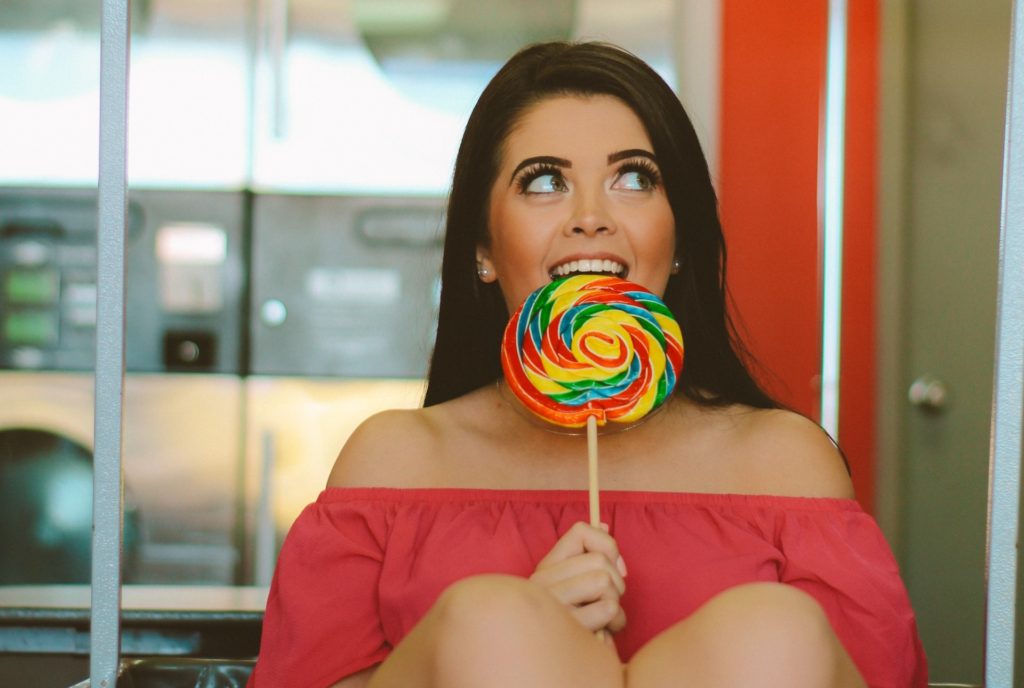 young woman eats a lolly with a smile